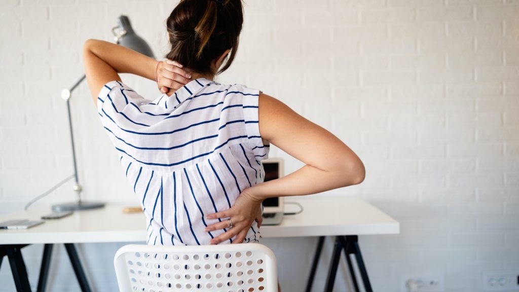 Overworked woman with back pain in office with bad posture