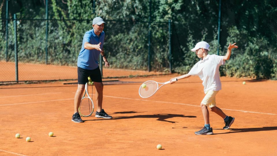 Tennis Instructor with Boy in Tennis Lesson.